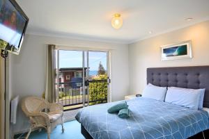 a bedroom with a bed and a large window at Lorne Ocean Sun Apartments in Lorne