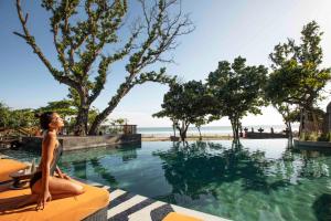 a woman sitting on a bench in front of a body of water at Hotel Indigo Bali Seminyak Beach, an IHG Hotel in Seminyak