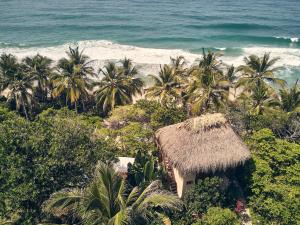 a beach with palm trees and a straw hut at Playa Los Angeles in Los Naranjos