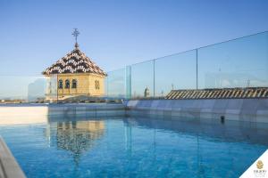 una gran piscina de agua con un edificio al fondo en Hotel Palacio De Úbeda 5 G.L en Úbeda