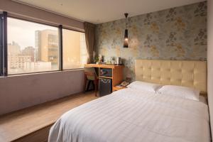 a bedroom with a bed and a desk and a window at Urtrip Hotel in Taipei