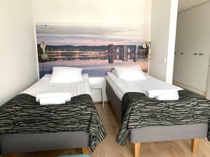 two beds in a room with a painting on the wall at The Harbour Apartments in Jyväskylä