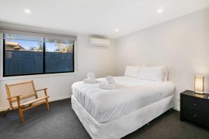 a bedroom with a bed and a chair and a window at Easy Living Bayside Accommodation in Tootgarook