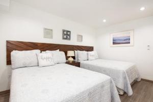 two beds in a hotel room with white sheets at La Casa de Paz Hotel in San Pedro