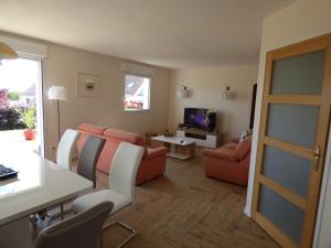 a living room with orange chairs and a television at Gîte du Marais d'Opale in Bazinghen