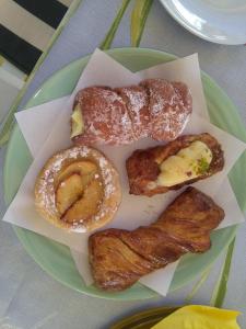 a green plate with donuts and bacon on a table at La Castellese in Aci Castello