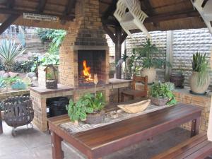 un patio con chimenea de ladrillo y banco de madera en See Rus Self catering unit in Westbrook KZN Private Neat and Cosy, en Westbrook