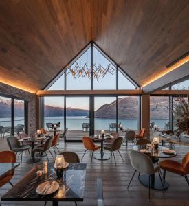 a restaurant with large windows and tables and chairs at Kamana Lakehouse in Queenstown