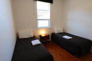 twee bedden in een kleine kamer met een raam bij Glenelg Holiday Apartments-Ellis in Adelaide