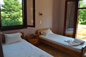 two beds in a room with a mirror and a window at Magdalini Studio in Anaxos
