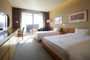 um quarto de hotel com duas camas e uma televisão em Rolling Hills Hotel em Hwaseong