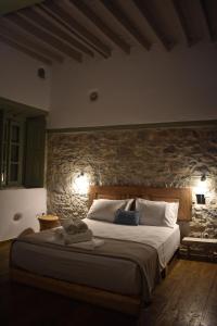 a bedroom with a large bed with a stone wall at Latmos 1860 in Skala