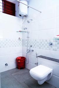 a bathroom with a toilet and a red bucket at UNNATHI SUITES in Mysore