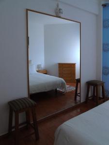 a mirror in a bedroom with a bed and two chairs at Cantinho Das Estrelas, Luz Lagos in Luz
