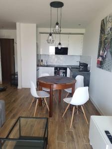 a kitchen with a wooden table and white chairs at Apartamenty Tychy Slaskie Ogrody in Tychy