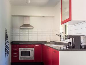 een keuken met rode kasten en een magnetron bij Vosseveen 62 in Zelhem