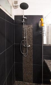 y baño con ducha y azulejos negros. en Loft & Espace Maison 1706 Lago Orta en Borgomanero