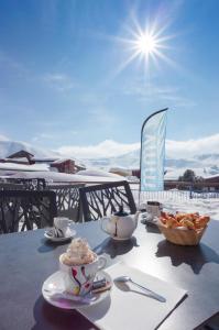 a table with cups and a bowl of food on it at Hôtel Club mmv Les Mélèzes **** in Arc 2000