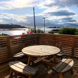 una mesa de madera y sillas en una terraza con vistas al agua en Tidal Cottage, en Ardvasar