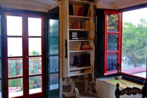 two windows in a room with bookshelves at Tramontana in Hydra