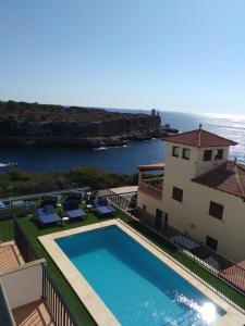 
a large white house with a blue ocean view at Hotel Rocamar in Cala Figuera
