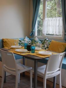 einem Esstisch mit weißen Stühlen und einem Tisch mit Gläsern in der Unterkunft Tiny house Dora in Marčana