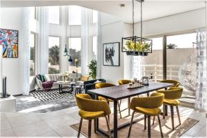 a living room with a dining room table and yellow chairs at One Perfect Stay - Jumeirah Heights in Dubai