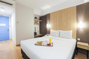 un grande letto bianco con un vassoio di cibo sopra di Hotel Citradream Bintaro a Serpong