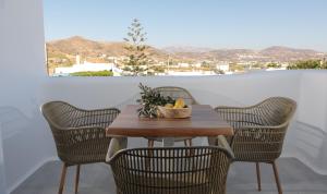 a table with chairs and a bowl of fruit on it at HORA SUITES in Naxos Chora