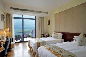 a hotel room with two beds and a large window at Sanya Serenity Coast Marina Hotel in Sanya