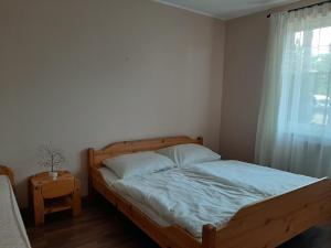 - une chambre avec un lit en bois et une fenêtre dans l'établissement Aqua Line Apartmanház, à Hajdúszoboszló