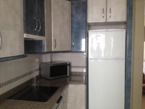 La cuisine est équipée d'un réfrigérateur blanc et d'un four micro-ondes. dans l'établissement Piso Nuevo Portil - Edificio Albatros, à El Portil