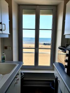 a kitchen with a window with a view of the beach at Appartement sur la Plage 4 Personnes in Arromanches-les-Bains