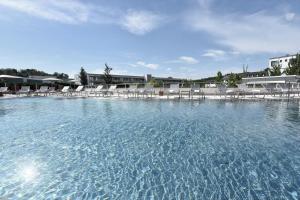 a large pool of water with lounge chairs in it at Reduce Hotel Vital in Bad Tatzmannsdorf