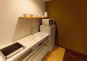 a small kitchen with a sink and a microwave at Irori Kyoto Station Higashi-Honganji in Kyoto