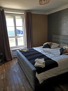 a bedroom with a large bed with a large window at Appartement sur la Plage 4 Personnes in Arromanches-les-Bains