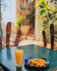 a plate of food and a glass of orange juice on a table at Hotel Pearl Palace in Jaipur