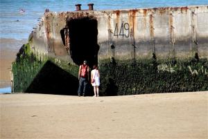 a man and a woman standing in front of a ship at Appartement sur la Plage 4 Personnes in Arromanches-les-Bains