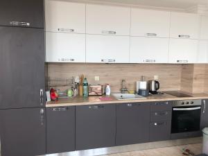 a kitchen with gray and white cabinets and a sink at Amazing apartment facing the sea in Burgas City