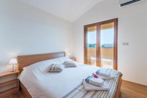 a white bedroom with a bed with two towels on it at Apartments Insula Aurea in Klimno