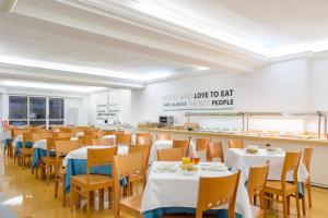 una sala da pranzo con tavoli e sedie bianchi di Hotel Vibra Vila a Ibiza Città