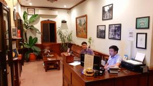 dos hombres sentados en un escritorio en una oficina en Pakhongthong Villa, en Luang Prabang