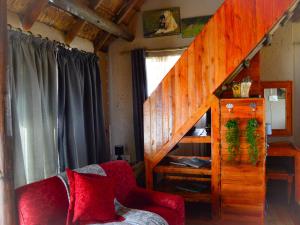 een woonkamer met een trap en een rode stoel bij Cheetau Lodge in Ebenhaezer