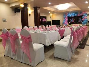 une grande table avec des chaises blanches et des archets roses dans l'établissement Huong Sen 2 Hotel, à Vung Tau
