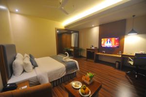 a hotel room with a bed and a flat screen tv at Pipul Padmaja Premium Hotel in Bhubaneshwar