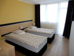 two beds in a hotel room with a window at Rómahegy Rendezvényház in Kaposvár