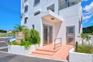 a white building with stairs in front of it at Comfort Villa in Motobu