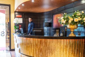 un hombre parado detrás de un bar en el vestíbulo en Hotel Silver Milano, en Milán
