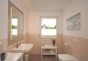 ein Badezimmer mit einem Waschbecken und einem WC sowie zwei Fenster in der Unterkunft Ferienwohnung Windherz in Ostseebad Sellin + 20 Fotos