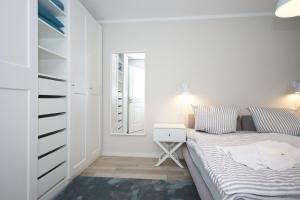 ein weißes Schlafzimmer mit einem Bett und einem Spiegel in der Unterkunft Ferienwohnung Windherz in Ostseebad Sellin